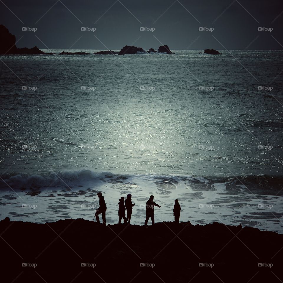 Coastal Moonlit Silhouette. A family of five silhouettes against a moonlit Ocean whilst standing on the shoreline rocks.