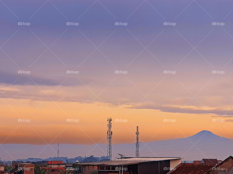 The sky is cloudy in morning, View in early morning, sky is covered by clouds and mist, clouds are red and yellow, the fog covers the view of mountain so that it looks gray