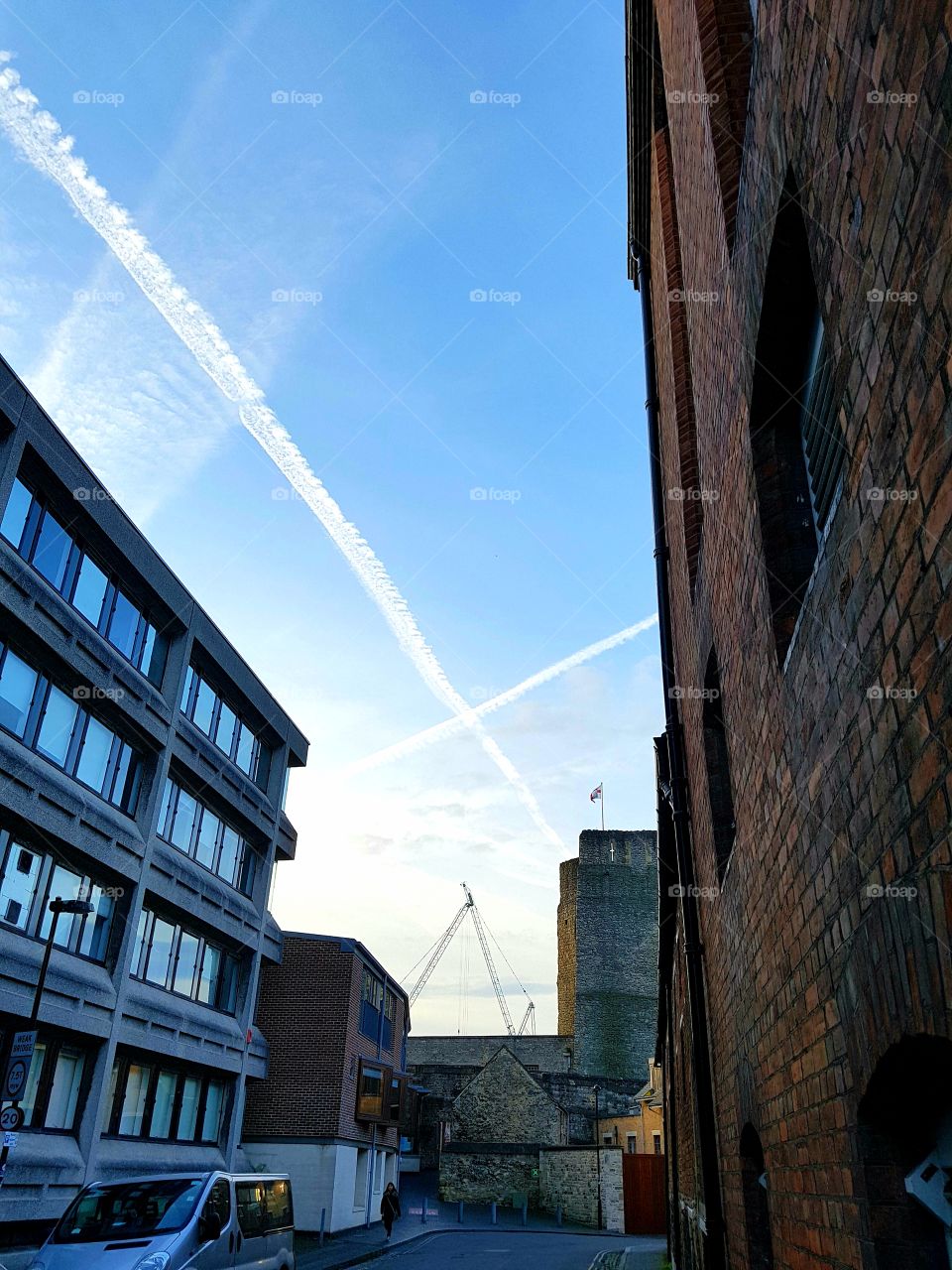 Plane trails over buildings and Oxford Castle