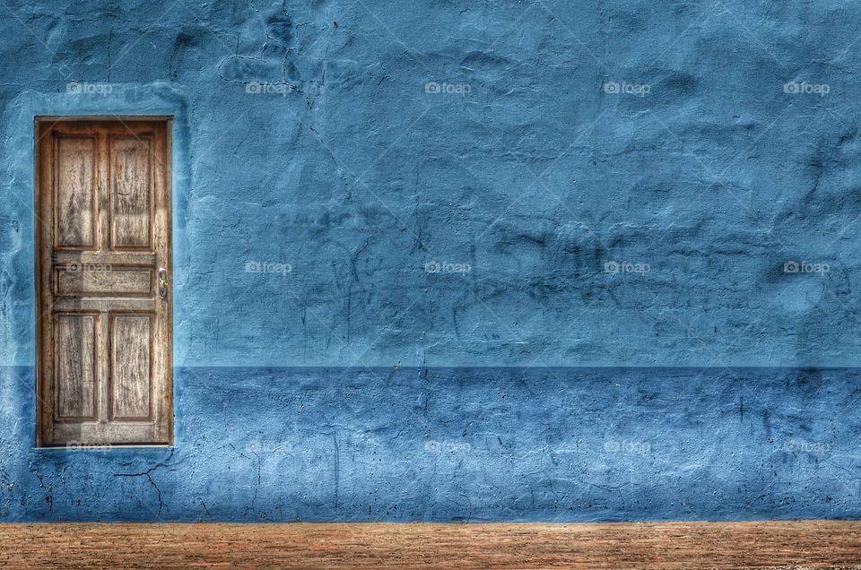 Wooden door and blue wall at day