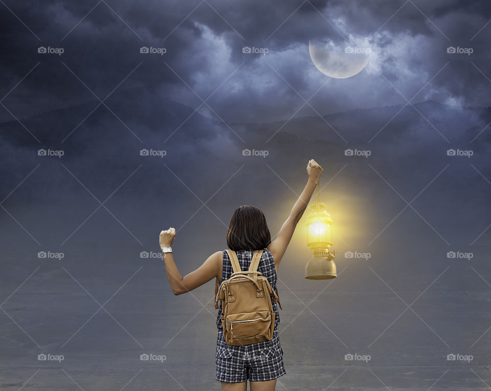 Hand woman holding the Old lantern Background moon and the shadow of the mountain at night with the black cloud.
