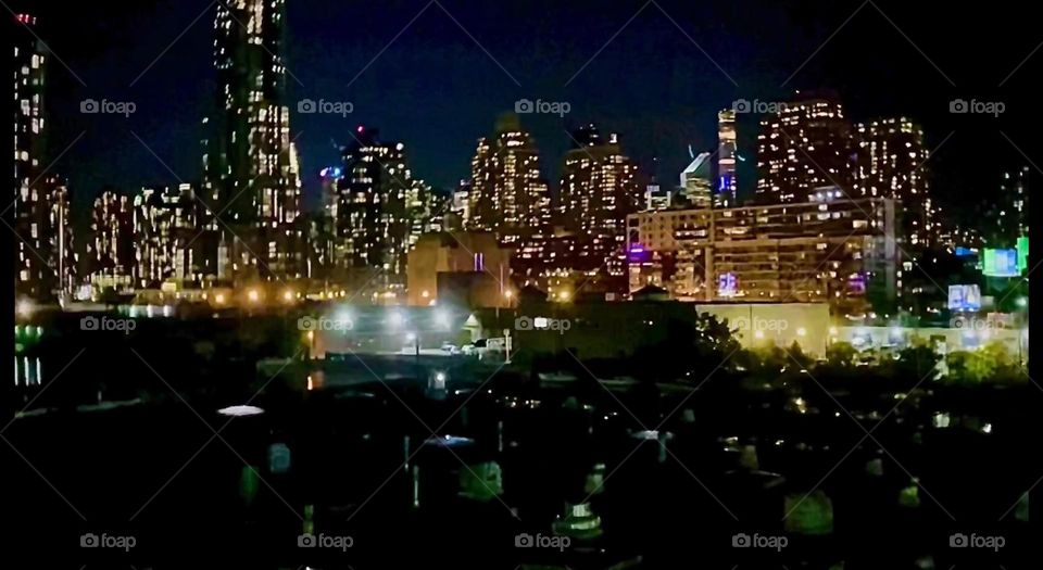 “Long Island City” and “Manhattan” seen from the pedestrian lane of the “Pulaski Bridge” at “Newtown Creek” at night can make an interesting motif when all the buildings and skyscrapers are illuminated and sparkle. 2023, Hypnotic Productions
