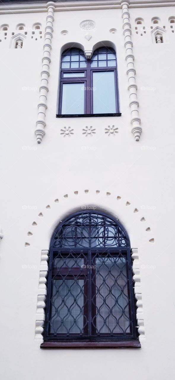 The facade of an old house on the windows, decorative cast-iron bars