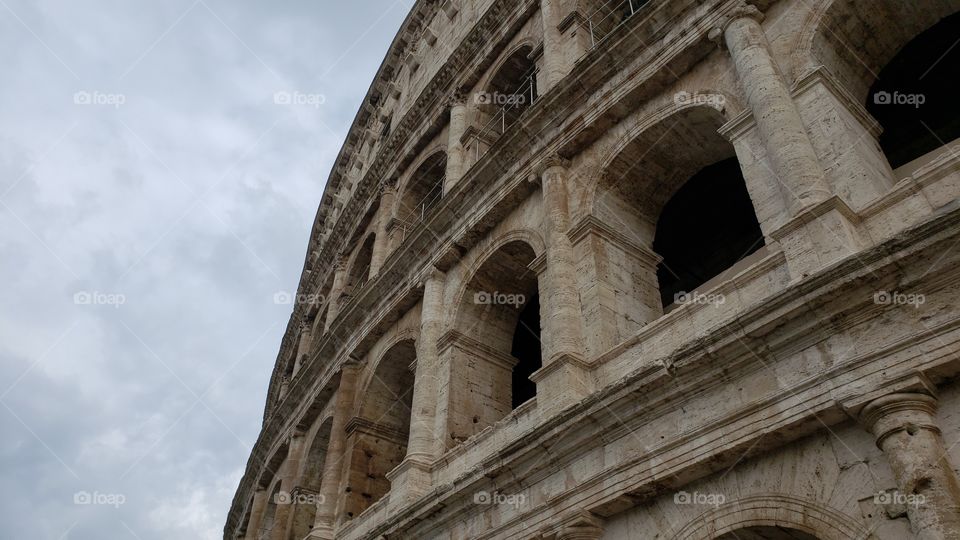 Side view up of the famous historic Colosseum in Rome, Italy, Europe, daytime with cloudy sky