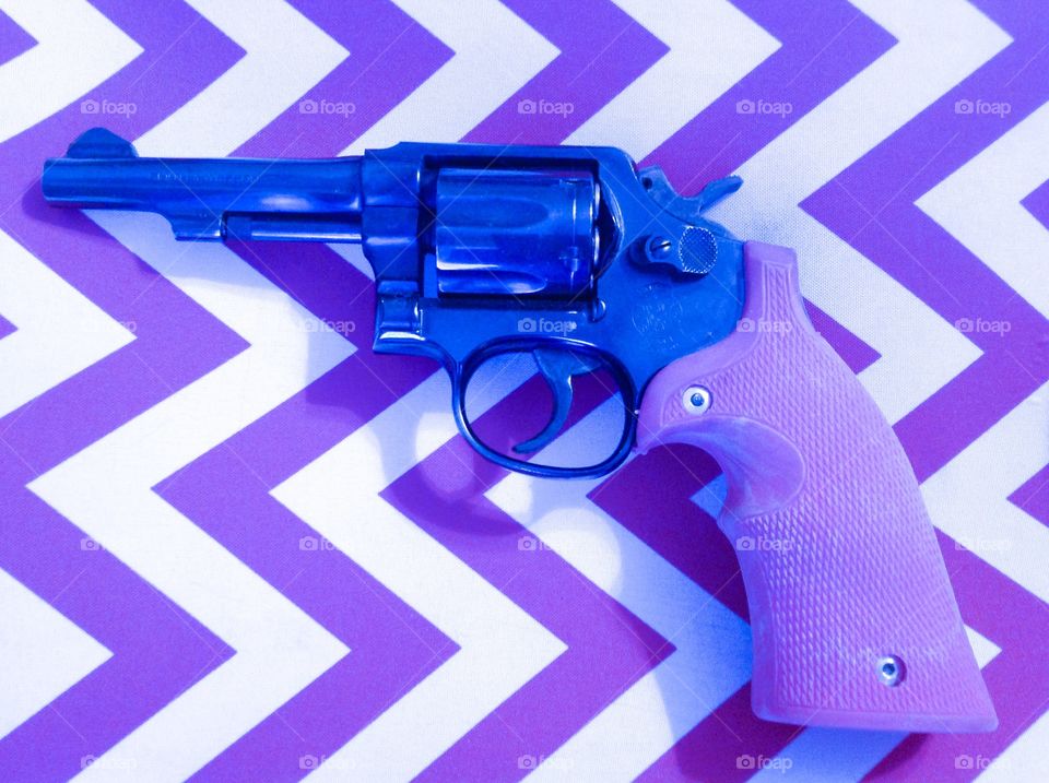 Purple Protection. Gun with purple grips on purple and white chevron background. 
