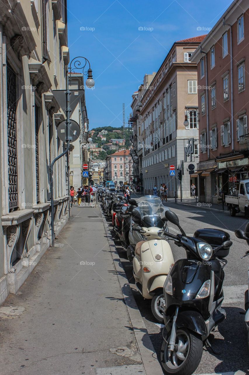 Scooters stand on both sides of the road.