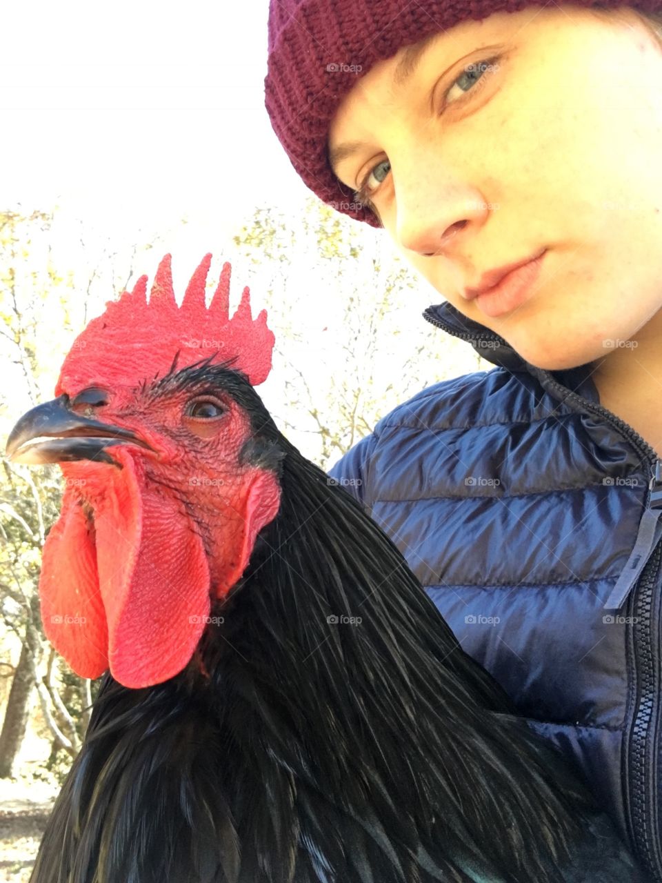 A young lady poses with her trusty rooster in her arms in autumn