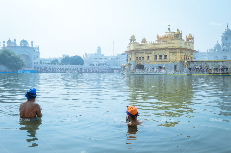 Unidentifiable Punjabi Sikh pilgrim devotee "Nihang Warrior" taking bath and prayer in pond and meditating in front of Golden Temple ("Harmandir Sahib Darbar Gurudwara") Amritsar, Punjab, India, Asia.
