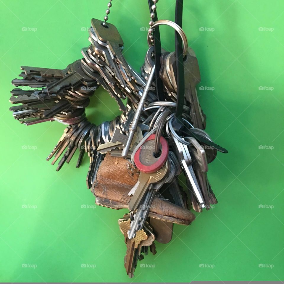 Many keys of all varieties hanging on a chain. Work keys of all types for use in many buildings. There's a small boot on this key chain. Skeleton keys, old used keys & keys that are marked for easy recognition.