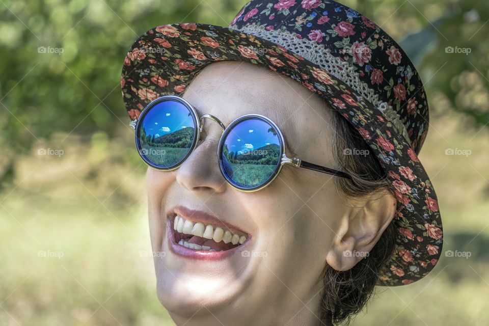 Beautiful smiling woman enjoying the mountain view. View is reflect in the mirror sunglasses