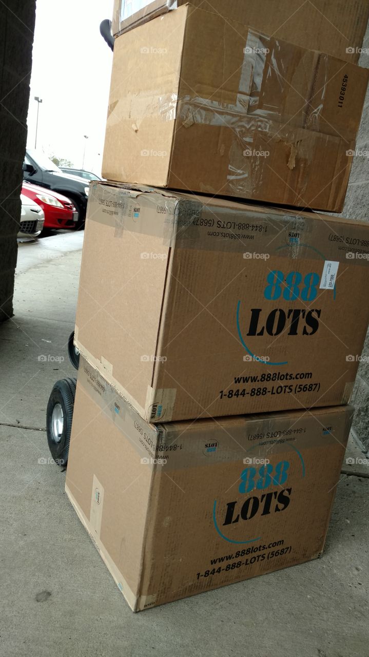 Cardboard shipping boxes are stacked outside a courier complex in an outdoor mall.