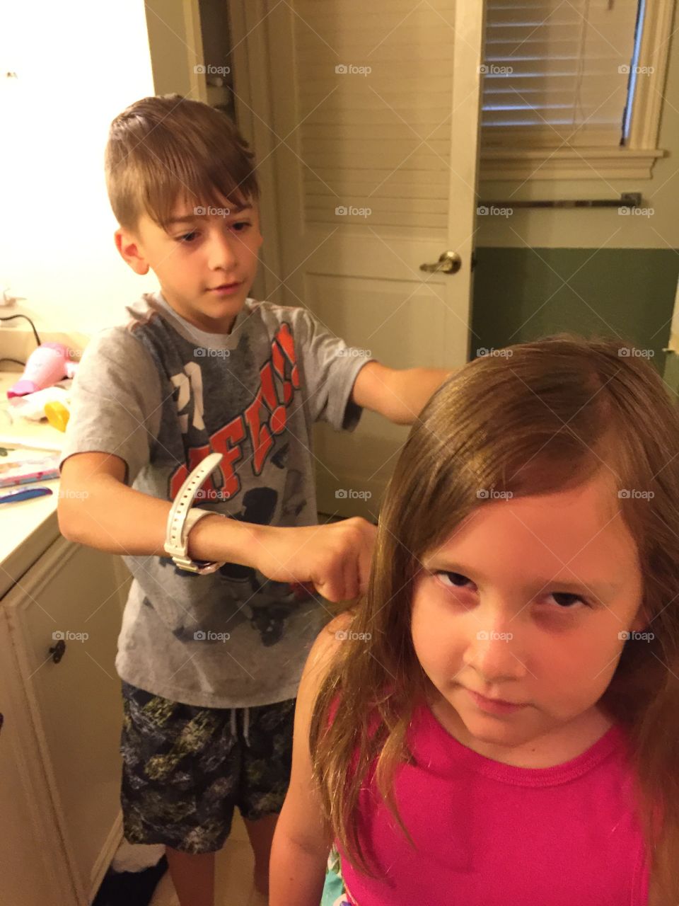 Brother brushing his sisters hair 