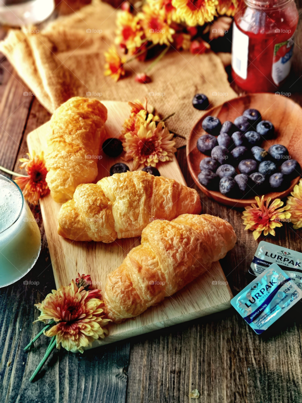 Croissants, blueberries, a cup of milk and some butter for breakfast 