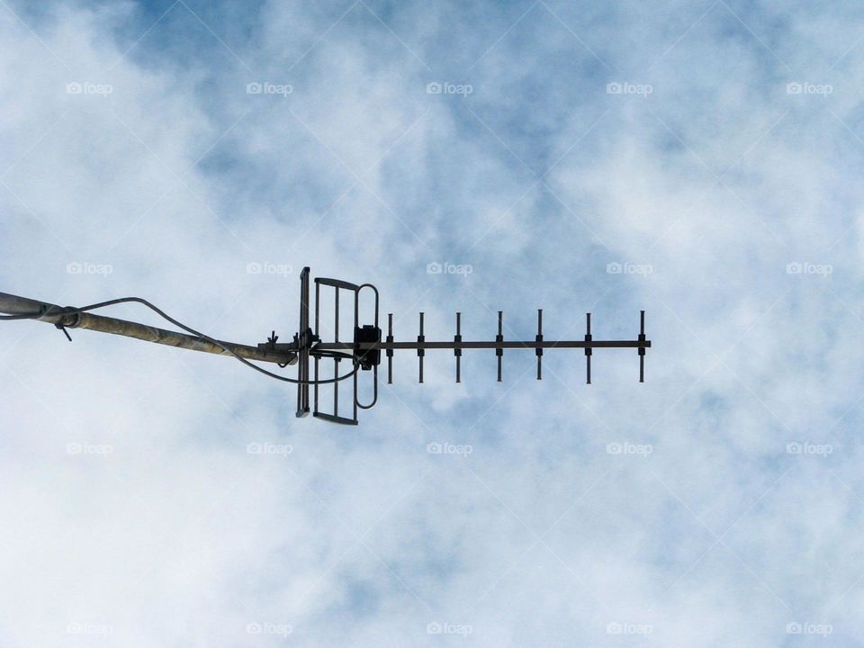 Close-up view of a television antenna installed outdoors against a cloudy sky background in low angle view