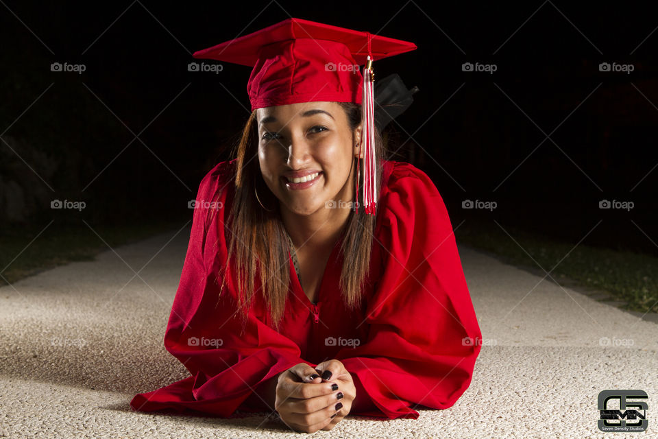Smiling woman in graduated gown lying