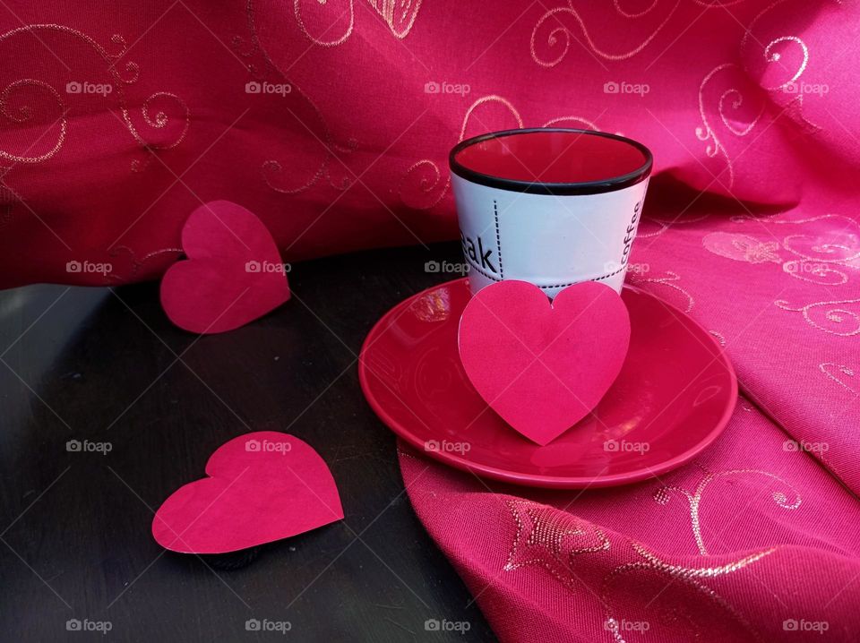 Cup on the table with tablecloth and hearts.  magenta paper