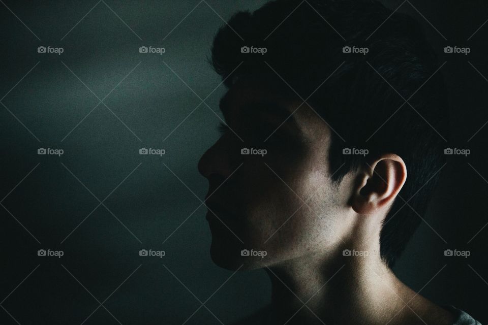 Young man in a dark room with harsh lighting