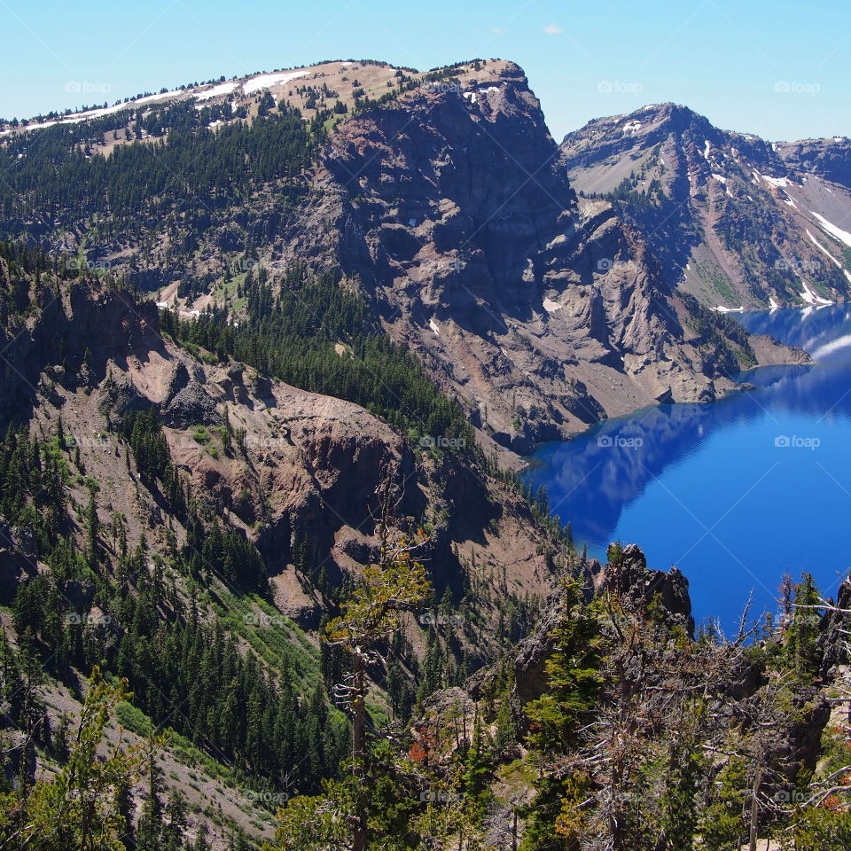 The rugged rim reflecting in the stunning Crater Lake on a beautiful summer morning in Southern Oregon. 