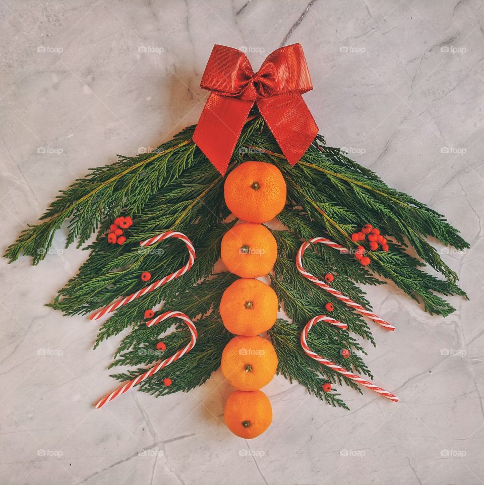 Christmas and New Year background with spruce branch, candies, decorations and tangerines Flat lay. Top view.