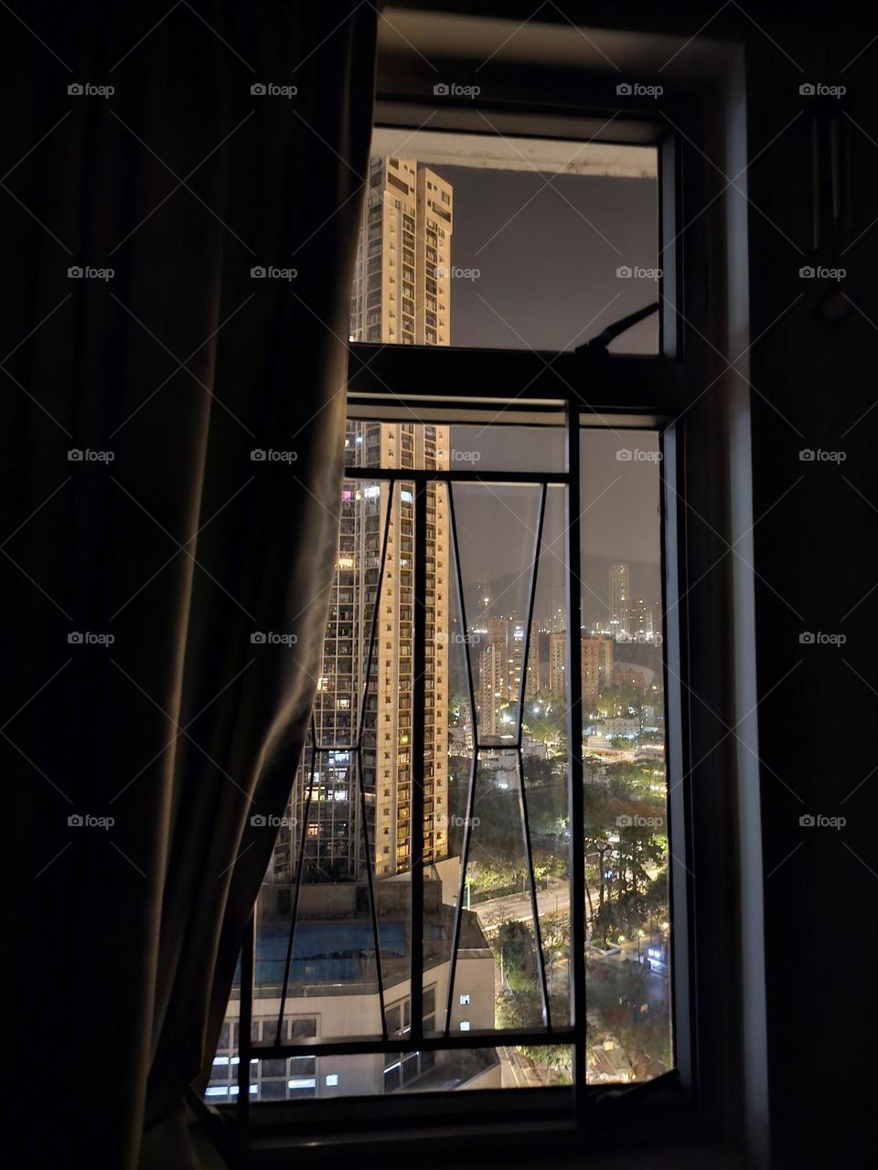 Looking out the window in the middle of the night in the dark room seeing Victoria Park,  Park Tower in Hong Kong