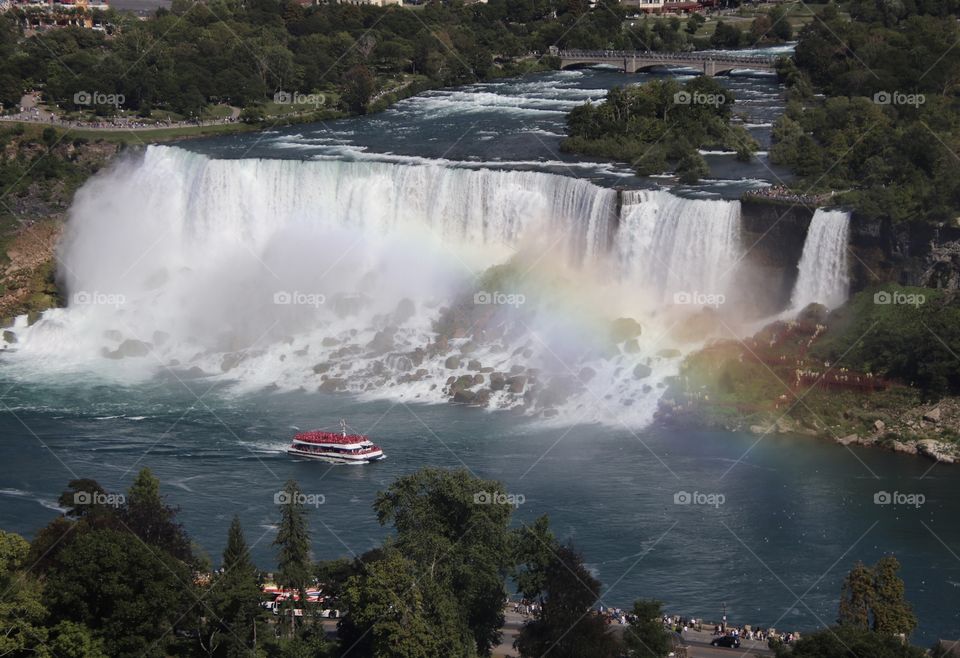 View of American Niagara Falls as seen from Canada showing red boat and rainbow in front of Falls
