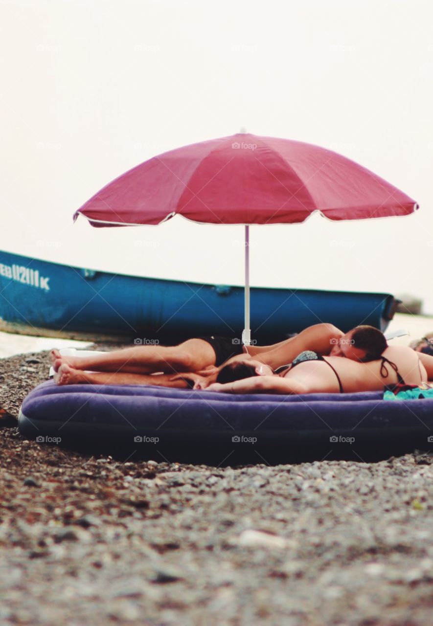 Couple at the beach under umbrella 