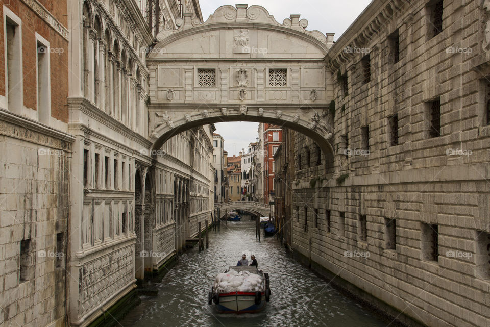 Waste collection boat rides underneath Bridge of sighs, Venice. 