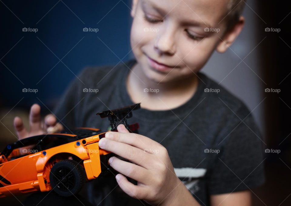 A boy assembles a race car model constructor