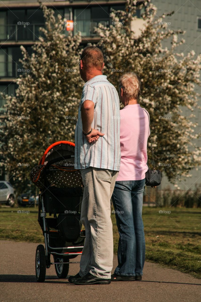 A elderly couple walking with the baby 