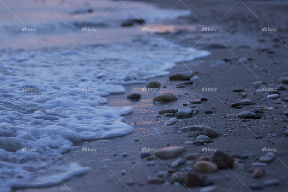 beach at sunset. sandy beach with small rocks at dusk