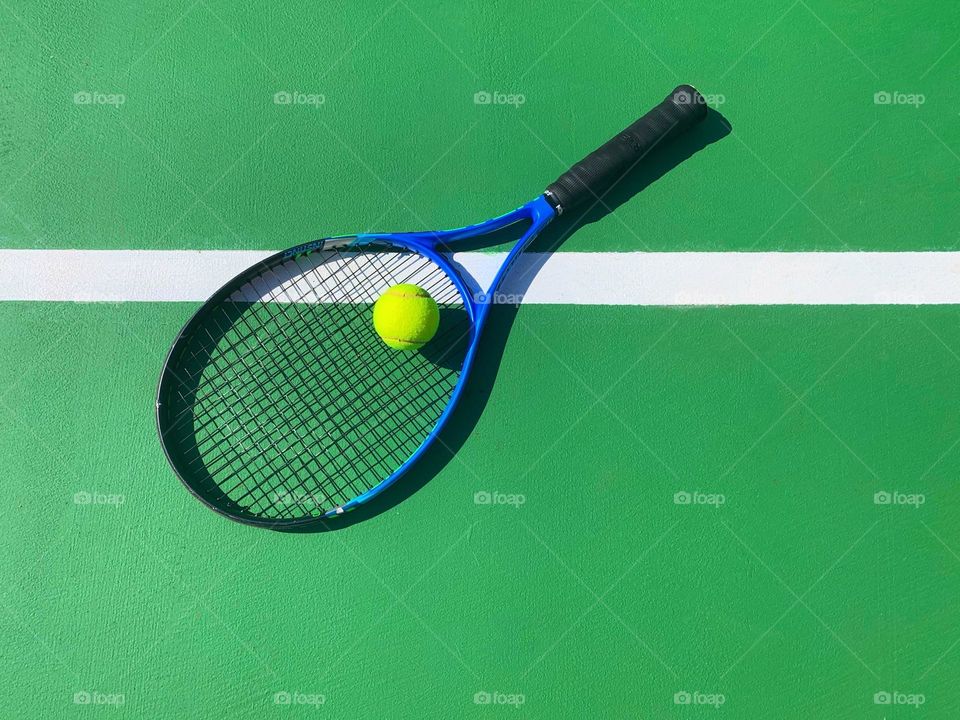 Tennis racket and ball on green court