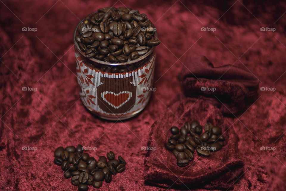 Fragrant coffee beans are scattered on a red background. Roasted coffee beans close up.