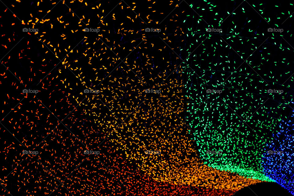 Tunnel of streaming holiday lights outdoors at night