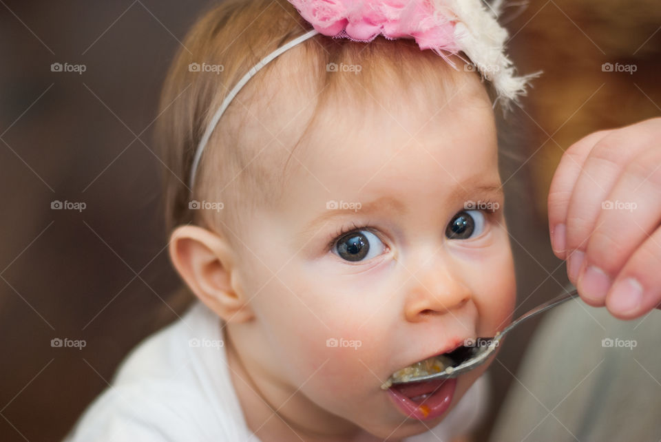 Person hand feeding baby girl