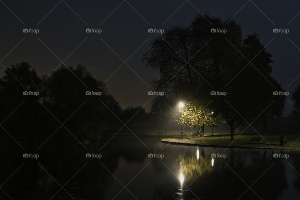 Late Night At The Lake. A dark night at the lake with a single artificial light illuminating a lonely corner.