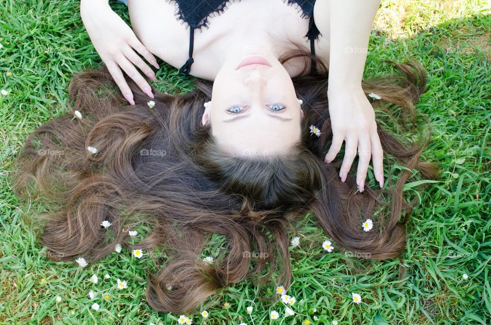 Portrait of a woman brunette with beautiful natural hair on background of daisies