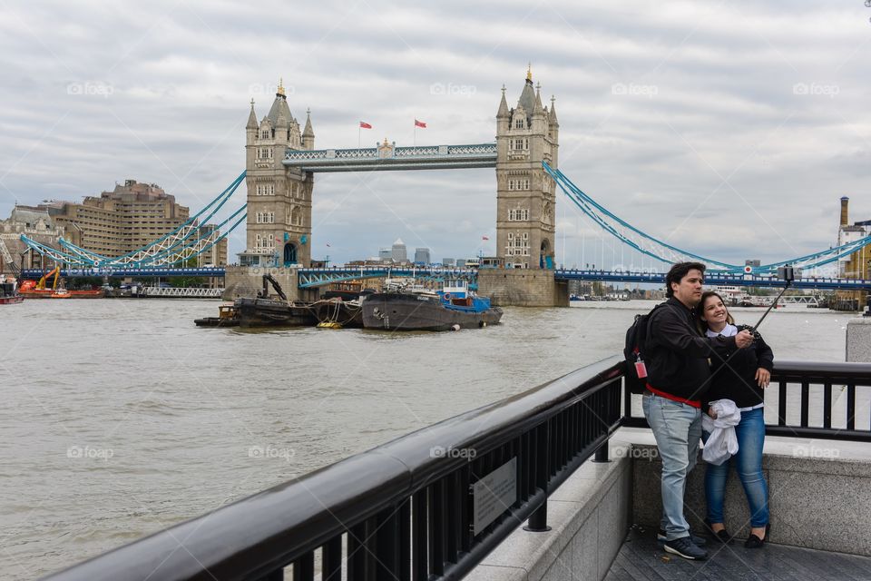 Tourist taking a selfie infront of Tower Bridge in London.