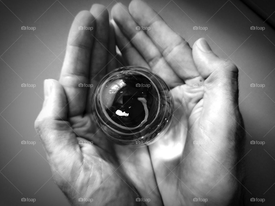 Hands holding glass art with a swirl. Black and white.