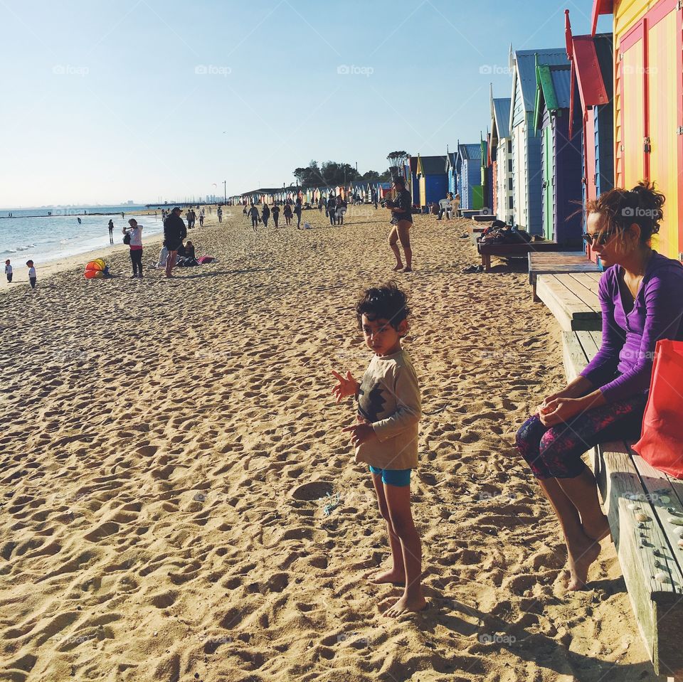 Beachgoers and bathing boxes on Brighton Beach in Melbourne, Australia.