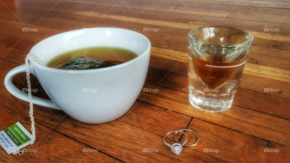Whiskey & Tea. A shot of whiskey  , a cup of tea and a some wedding rings