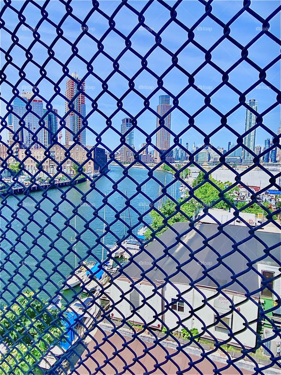 The “harbor area” that is “Newtown Creek” as seen through a metal mesh fence from the pedestrian lane on the famous “Pulaski Bridge” overlooking the “East River” in the summertime of 2022. Hypnotic Productions