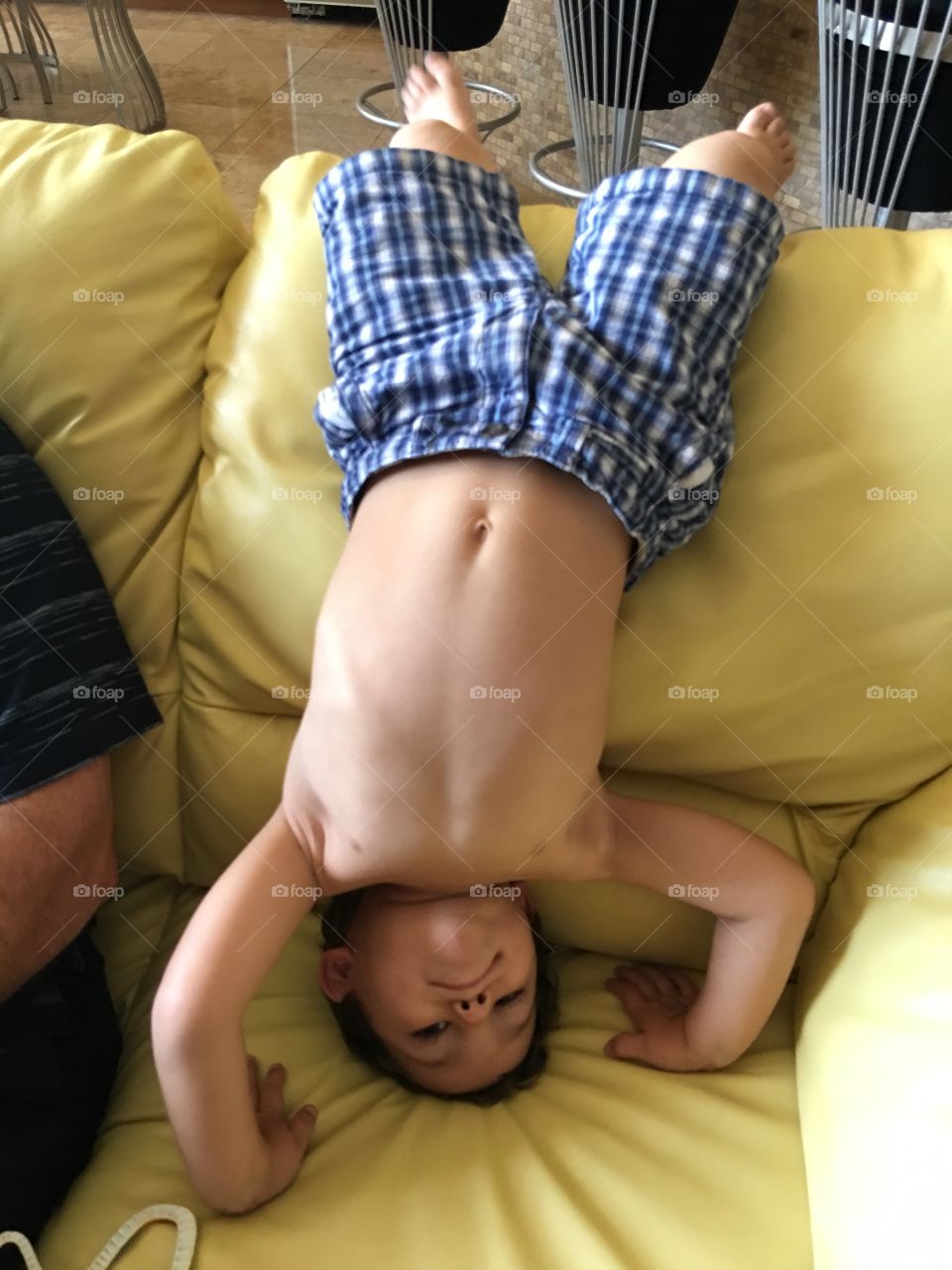 Boy hanging upside down on sofa.