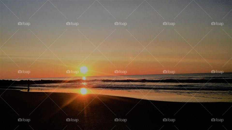 sunrise over Pawleys Island SC reflecting in the shallow waters on the beach