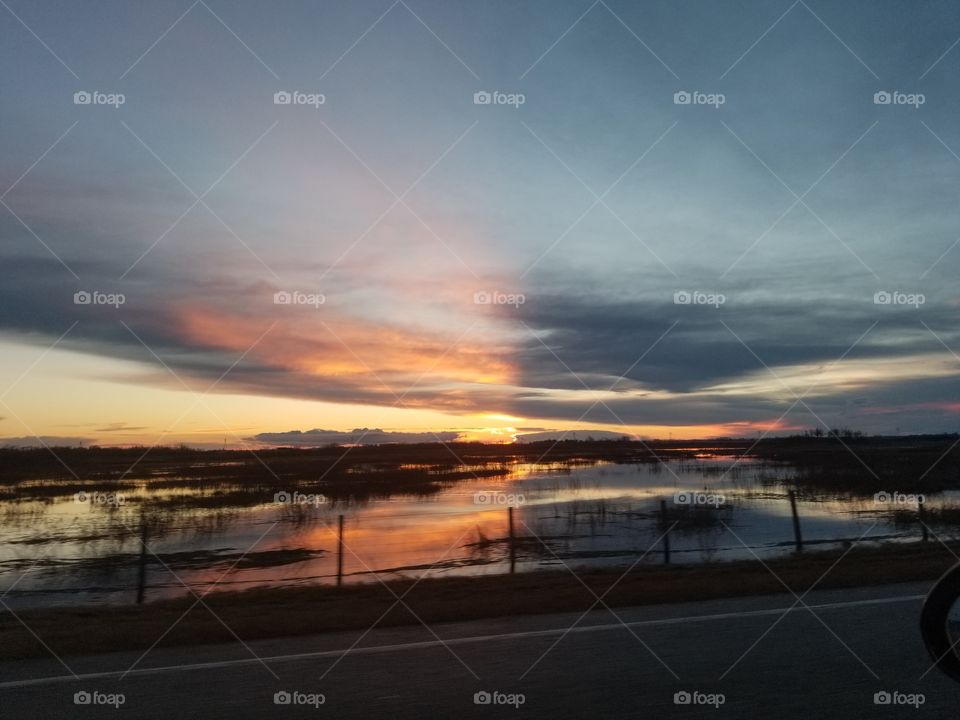 sunset in Alberta, Canada. orange and blue divide over an animal filled lake off the highway 110km per hour.