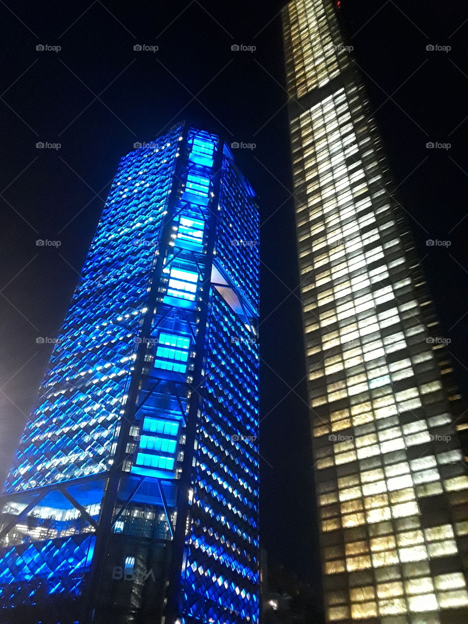 edificios torres con luz iluminadas de color blanco y azul.. de fondo negro en la ciudad