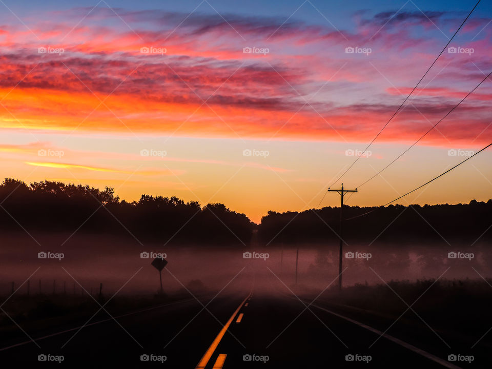 Road through dawn lit mist