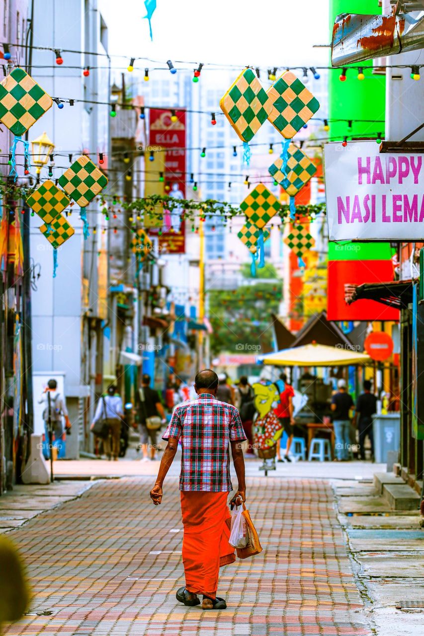 A man is walking down the street with colourful backi