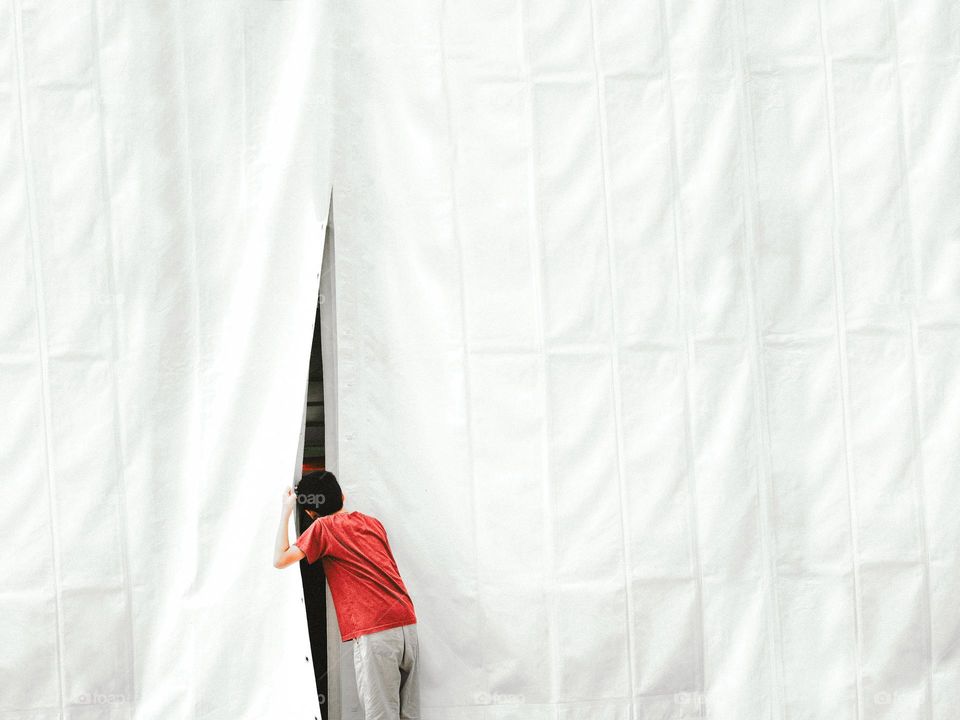 A boy peeping through an opening in the tent