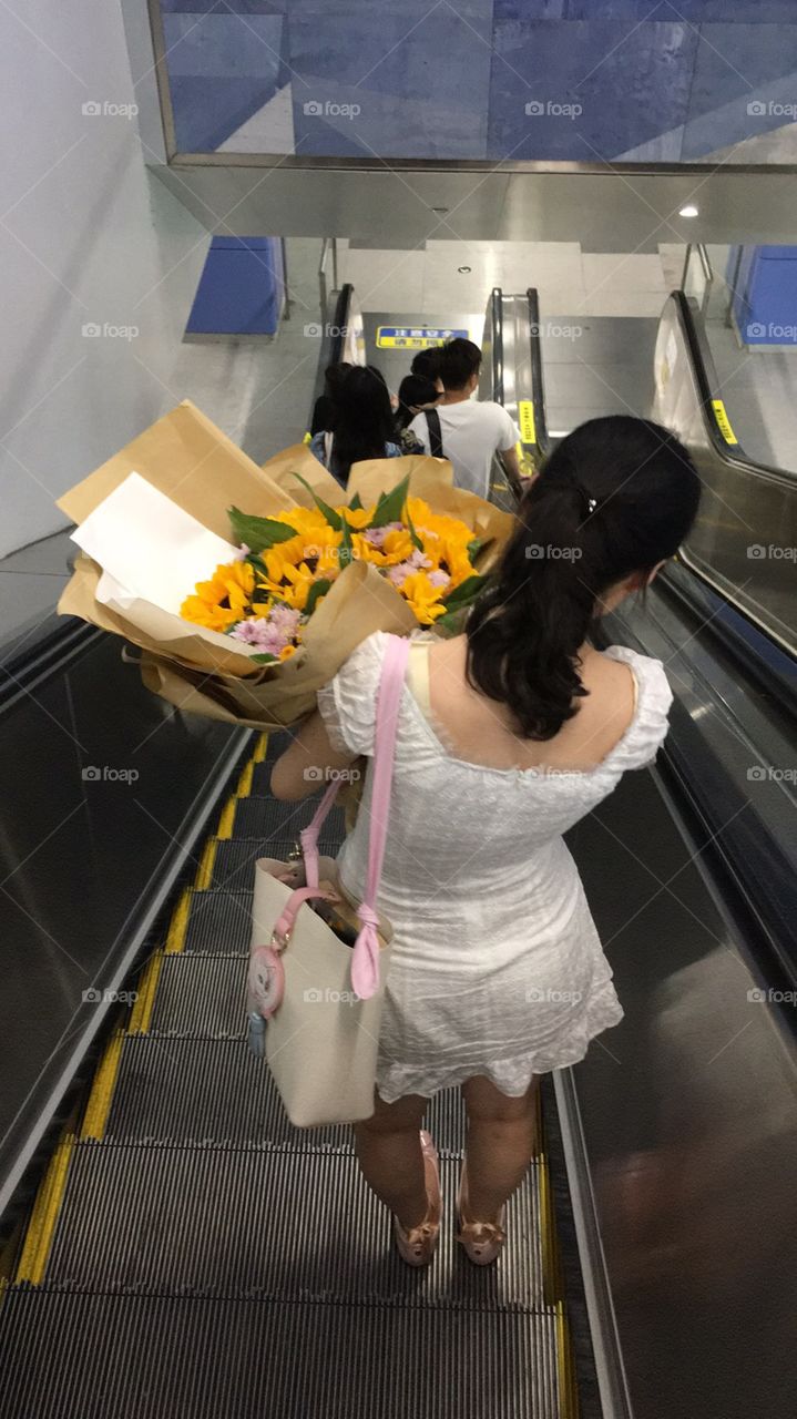 A girl with flowers on a escalator 