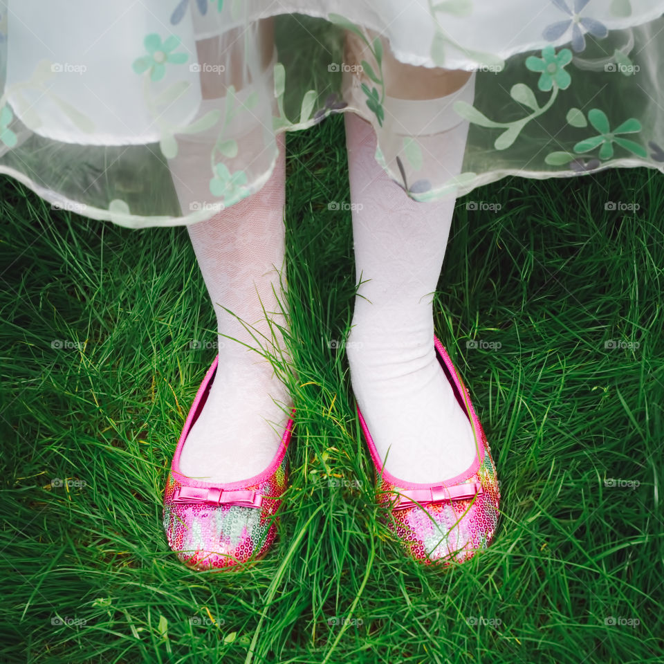 Pink on green. Close up of colorful shoes of young girl